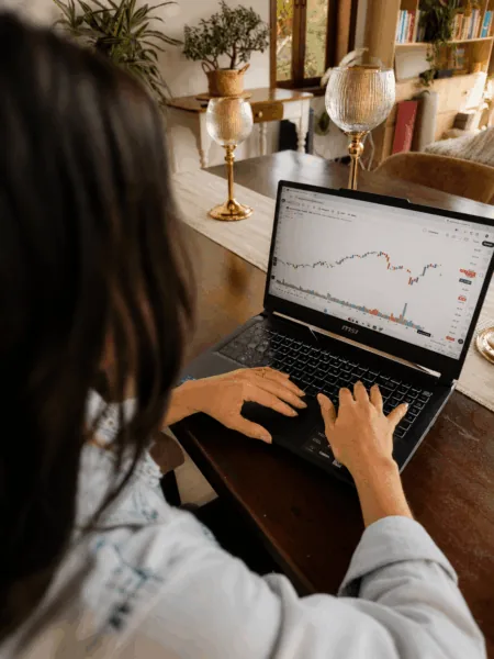 Inversionista analizando un gráfico de velas japonesas y volumen en su computador portátil